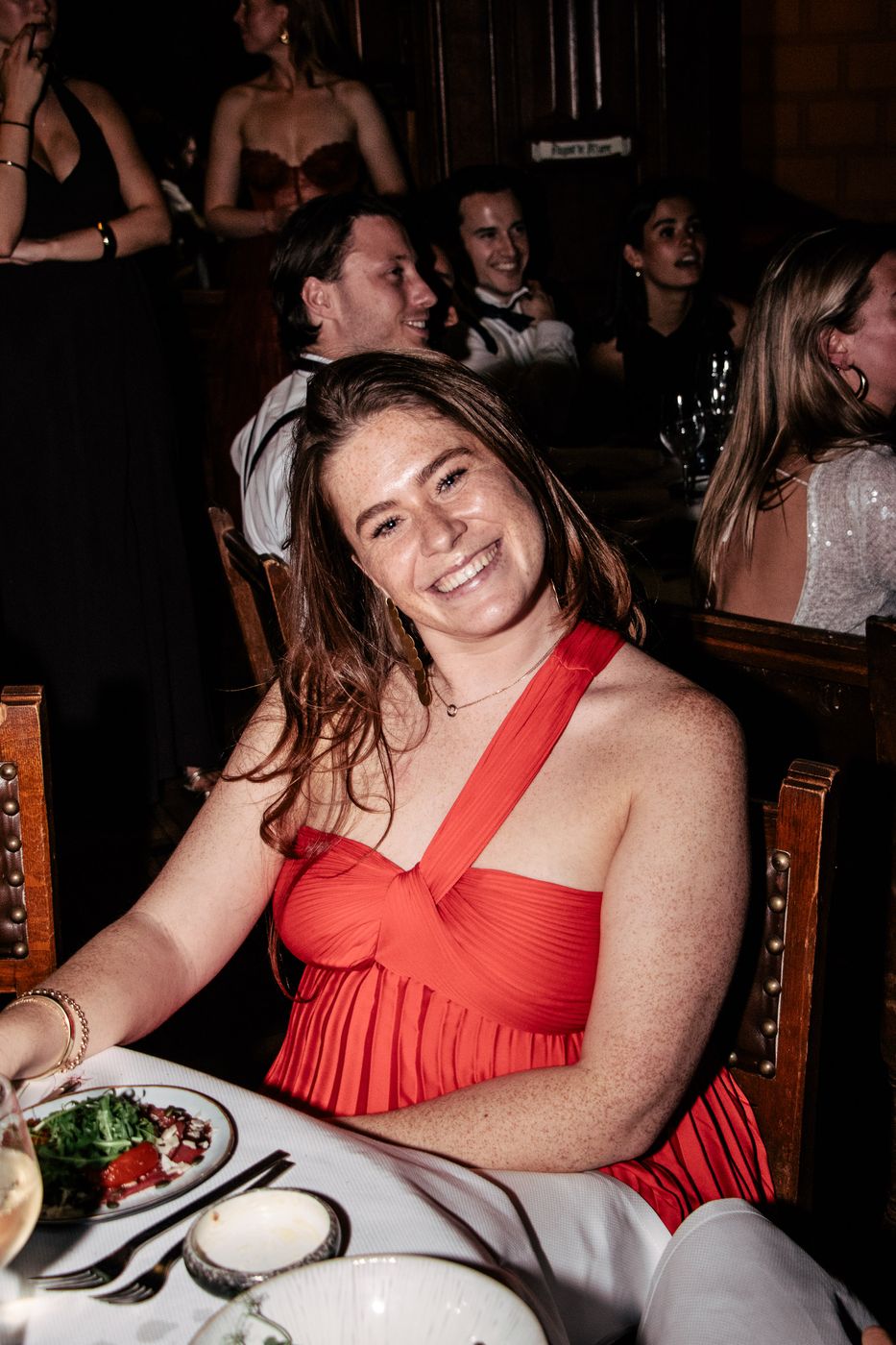 Gast in een rode jurk aan tafel, gefotografeerd met flits